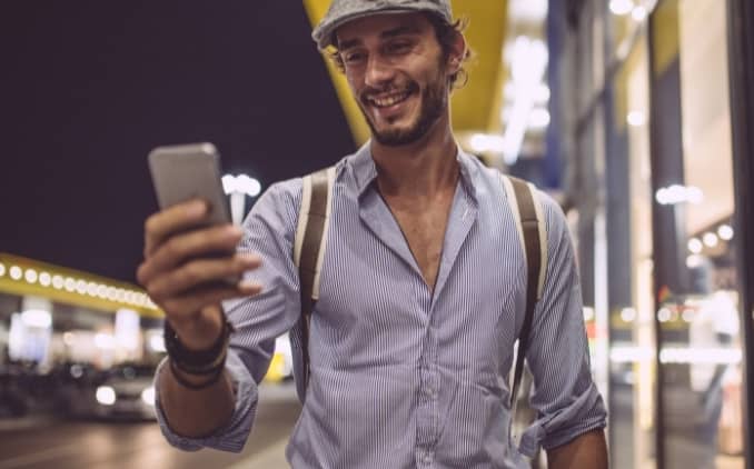 Hombre de personalidad y apariencia atractiva caminando en la calle recibiendo un mensaje de texto de una chica