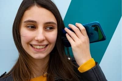 Chica bonita con el celular al oído escuchando un menaje de audio